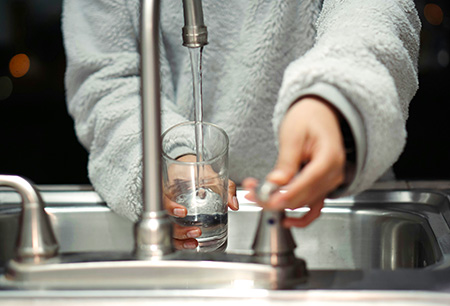 Person getting a glass of water at a kitchen sink